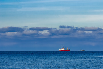 Red fishing ship sailing far in the Baltic sea. Europe