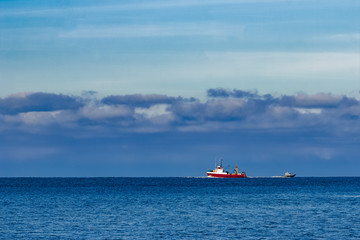 Fototapeta premium Red fishing ship sailing far in the Baltic sea. Europe