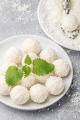 Homemade coconut candies in a white plate on the table. Sweets. Selective focus