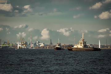 Two tug ships are accepting cargo vessel at Daugava river