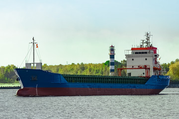 Blue cargo ship leaving the port of Riga at sunny day