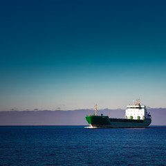 Green cargo ship moving in still water of Baltic sea