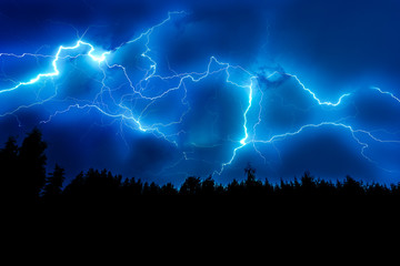 Lightning strike on a dark blue sky over the forest silhouette