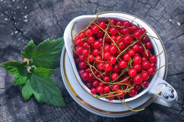 ripe red currant in an old ceramic vase on a wooden background
