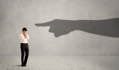 Business person looking at huge shadow hand pointing at him concept