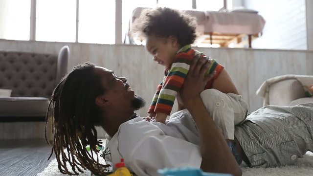 Cheerful father and toddler son having fun at home