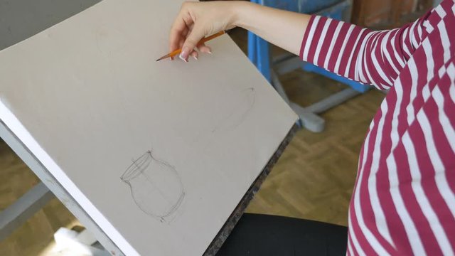A young artist in an art workshop draws a still life of a sketch from nature in pencil.