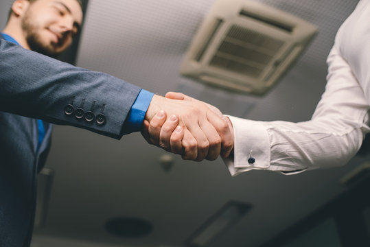 Two men handshaking in an office after successful contract