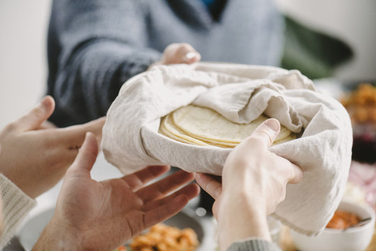 Cropped image of friends passing tortilla while having food at table