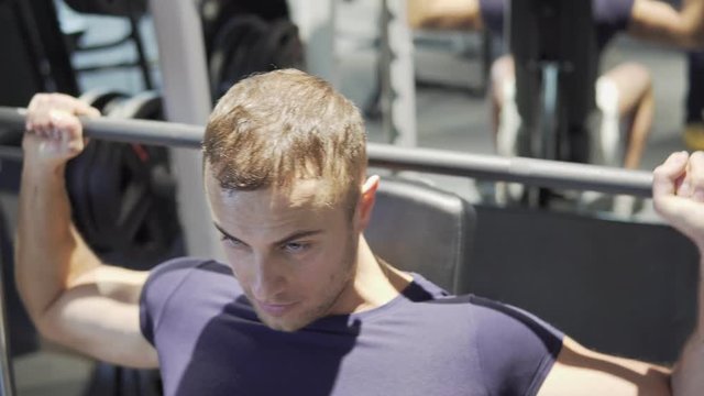 Handsome sporty man is exercising in gym centre