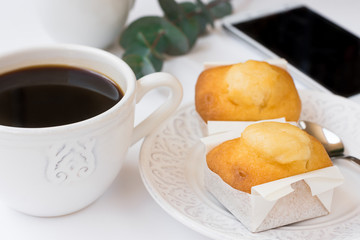 Smartphone, cup with coffee, pastry on plate, eucalyptus branch on white table, business, female blogging, styled image