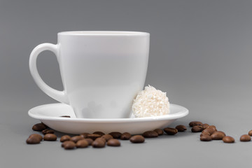 White cup of coffee with candy on a gray background