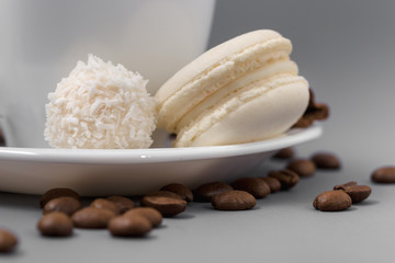 White cup of coffee with candy on a gray background