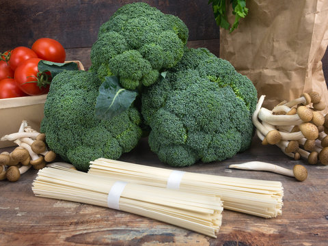 Still life vegetables cabbage broccoli with tomatoes mushrooms spaghetti green leaves wooden background