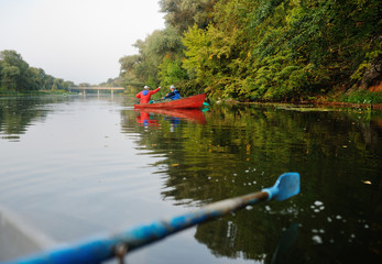 Two fishermen in a boat with fishing rods catching fish
