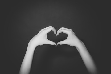 Obraz premium Woman hands making a heart shape on the black background