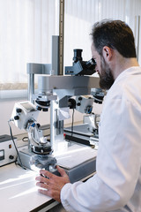 Scientist in laboratory looking through microscope