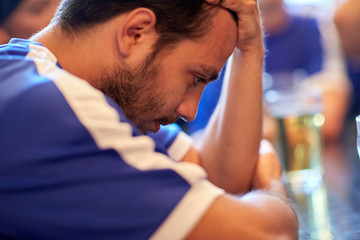close up of sad football fan at bar or pub