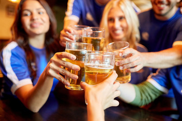 football fans clinking beer glasses at sport bar
