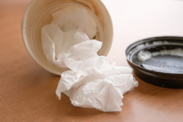 Takeaway coffee cup lying on wooden table with lid near