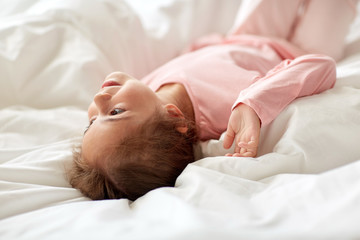 happy little girl lying in bed at home