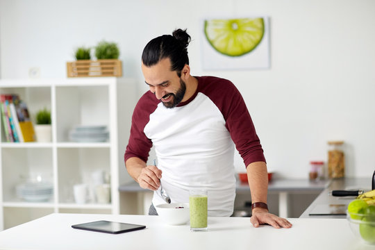 man with tablet pc eating breakfast at home