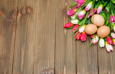 Bouquet of tulips and eggs on a wooden background