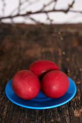 Three Easter eggs of red color on a blue plate