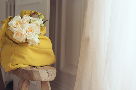 sac en lin avec des roses pos&eacute;es sur un banc