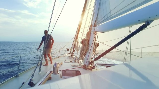 Mann auf Segelyacht / Segelboot segelt in die Abendsonne