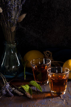 Rustic still life with tea or liqueur drink, citruses and lavender