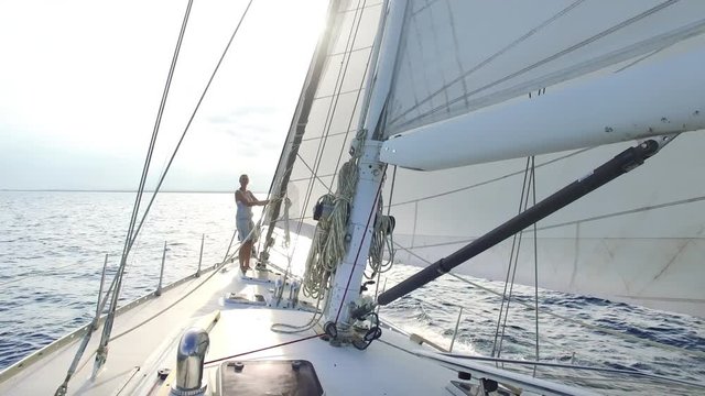 woman on big sail boat sailing the ocean - nice sun flares