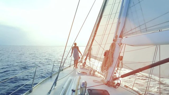 woman on big sail boat sailing the ocean - nice sun flares