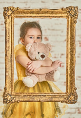 Indoor portrait of an expressive adorable young little girl and her Teddy bear friend seen from an...
