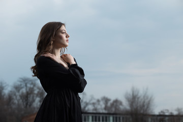 Beautiful woman in black dress against sullen sky background