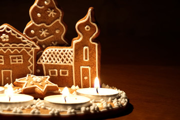 Homemade gingerbread house lit by candles on a dark background. Christmas dessert 
