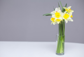 Posy of bright yellow daffodils on white wooden table