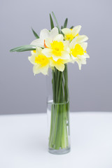 Posy of bright yellow daffodils on white wooden table