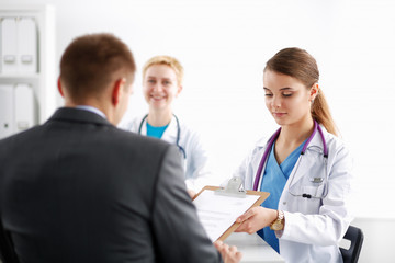 Fototapeta premium Beautiful young smiling female doctor sitting at the desk