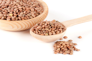 Lentils in a wooden bowl with a spoon isolated on a white background