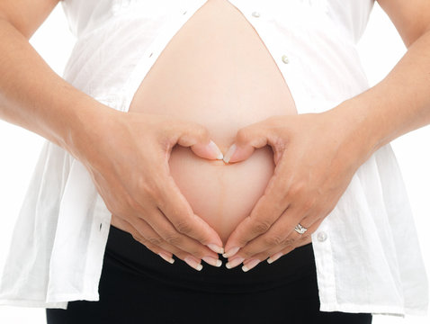 Hands forming heart shape on pregnant belly on white background