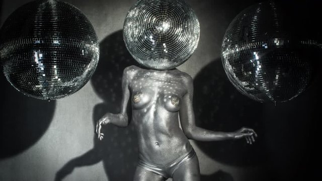 Female disco dancer in silver body paint and disco ball as head
