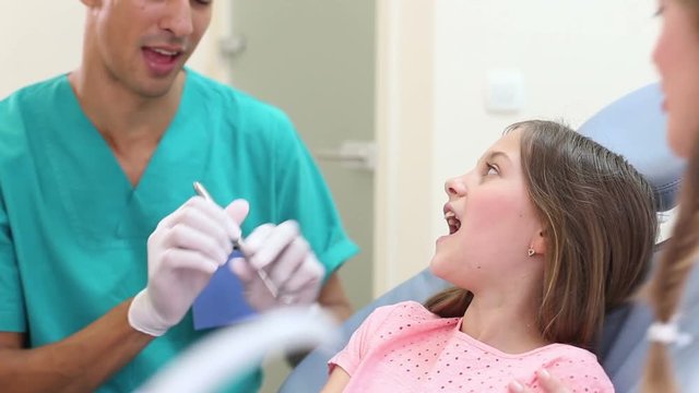 male dental surgeon and beautiful little girl doing high-five after teeth checkup