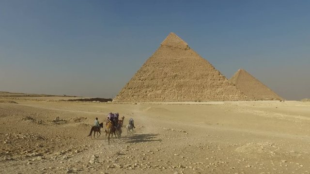 Tourists riding camels at Giza pyramids