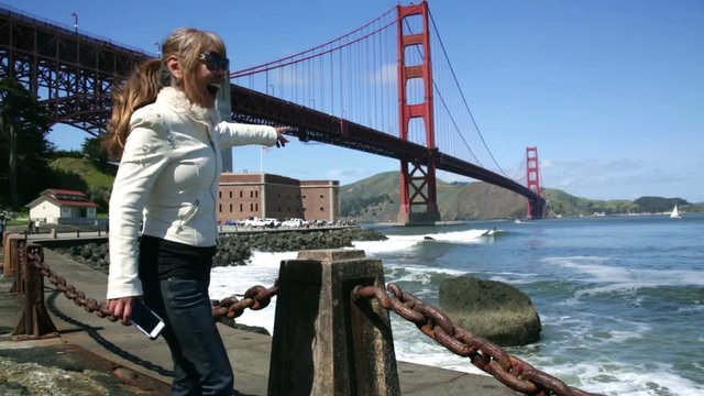 Fit Adult Woman and Tourist at Golden Gate Bridge pointing and taking pictures