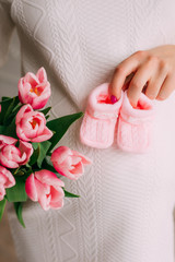Belly of pregnant girl and tulips in hands