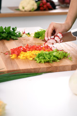 Close up of  woman's hands cooking in the kitchen. Housewife slicing ​​fresh salad. Vegetarian and healthily cooking concept