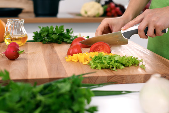 Close up of  woman's hands cooking in the kitchen. Housewife slicing ​​fresh salad. Vegetarian and healthily cooking concept