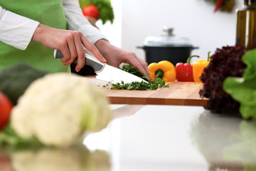 Closeup of human hands cooking vegetables salad in kitchen on the glassr table with reflection. Healthy meal and vegetarian concept