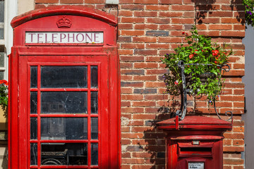 Traditional red post box and the phone booth near a brick wall in Sidmouth, England, United Kingdom